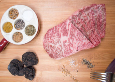 A table with a Raw steak, spices and Truffle on it