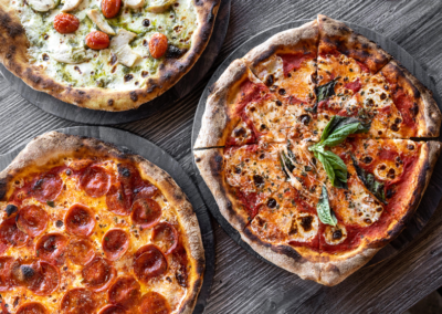 3 different flavours of pizzas on a wooden table