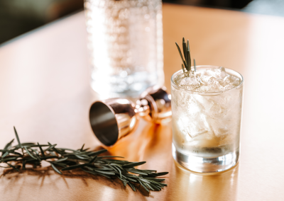 A cocktail made in madam bonnies topped with some herbs