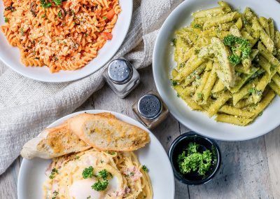 alt="three plates of pasta, broccoli and bread on a table from a client of formula marketing an advertising agency in san diego"