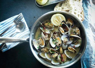 alt="a pan filled with clams and lemon slices"